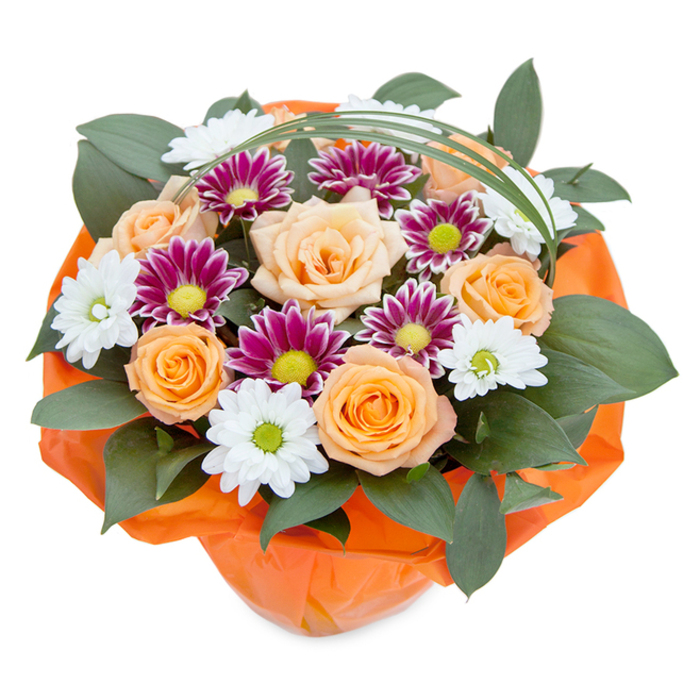 Elevated for a striking view, this lush bouquet showcases a harmonious medley of fresh blooms, capturing the refined taste and natural beauty valued in Gerrards Cross. At its heart, large roses bloom in a tapestry of tender peach and sunlit orange-their central petals tightly furled and the outer layers unfurling in soft waves, suggesting the gentle unfolding of community and friendship. Between them, elegant chrysanthemums appear in two forms: snowy white daisies with vibrant green or yellow-green centers, and densely petaled magenta-purple varieties with bold lime cores, their colors popping like joyful celebrations at East Common. Thick, glossy leaves-likely robust ruscus-thread through the composition, offering deep green contrast, lush texture, and the sense of a garden after rainfall. Adding a refreshing modern note, a slender loop of bear grass bends gracefully over the blooms, its arc echoing the contemporary yet welcoming style seen in Gerrards Cross's homes and shops. The bouquet is meticulously gathered at the base in lively, crinkled orange cellophane, not only shaping the display but uniting the arrangement's warm palette. Every detail, from the careful grouping of flowers to the vibrant wrap, speaks of thoughtful design and local expertise-ideal for gifting or bringing a burst of color to homes near Gerrards Cross Common. Evoking celebration and appreciation, this arrangement stands as a true testament to the artistry of local floristry.