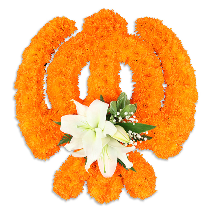The Khanda's sacred silhouette is rendered here with artful precision: thousands of vivid orange marigold heads are assembled into a dense, textured form that defines the circular chakkar, the two crossed kirpans and the upright double-edged khanda at the centre. The marigolds' compact, velvety petals create a warm, radiant surface that captures light and shadow, imparting a sculptural depth that is emphasised by the faint drop shadow beneath the display, indicating it is a freestanding devotional piece. Anchoring the composition where the kirpans intersect, a refined cluster of white lilies-two or more fully open blossoms with gently curved petals and understated yellow-green stamens-offers a serene focal point; a few smaller buds and tender white gypsophila sprays surround them, while glossy green foliage provides structure and cool contrast. The overall palette-saturated orange, pure white and fresh green-balances exuberance with solemnity, suitable for Vaisakhi processions, Gurpurab decorations, and respectful memorials within local Sikh communities. The arrangement's craftsmanship signals careful handwork: flowers placed densely for continuity of line, filler chosen to soften edges, and proportions kept true to the symbol's geometry. For people in Gerrards Cross, Chalfont St Peter and the surrounding villages, this piece reads as both an offering and a work of floral art-a colourful statement of faith and unity that carries scent, texture and cultural meaning in equal measure.