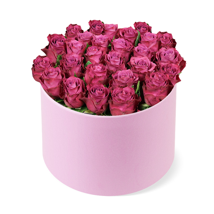 A round hat box of roses stands alone against a pristine white background, the simplicity of its setting allowing every nuance of colour and texture to shine. The roses, in shades of deep fuchsia and jewel-like magenta, are arranged with meticulous precision, their heads aligned to create a perfectly domed surface that seems almost sculpted. Each flower appears at peak freshness, petals tightly layered yet just beginning to open, revealing pale pink whorls at the centre and gradually deepening towards the outer edges into intense, berry-toned purples. The blooms are so densely packed that they rise in a plush cushion above the top of the container, overflowing in a way that suggests pure abundance. The cylindrical hat box is a gentle, light pastel pink, its matte, almost velvet-like finish adding a tactile softness that mirrors the feel of rose petals brushed against the fingertips. Only minimal flashes of dark green foliage break through near the base of the flowers, used sparingly so the focus remains firmly on the rich colour of the roses. A delicate shadow beneath the box grounds it on the smooth white surface, while the bright but diffused lighting creates a sense of clarity without harshness. As a local florist serving Gerrards Cross and nearby Chalfont St Peter, I see this arrangement as ideal for an elegant anniversary weekend at home near West Common or a luxurious thank-you gift delivered to an office close to the station, an image that conveys romance, high-end craftsmanship, and the quiet thrill of receiving something truly special.
