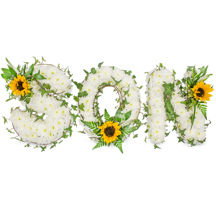 A sculpted, three-dimensional sympathy display that spells SON in capital letters, each letter robustly formed from a uniform carpet of small, pristine white chrysanthemums whose compact heads produce a soft, pillowy texture. The white chrysanthemums are densely wired and layered to create crisp, readable letterforms set against a stark white photographic background, the even studio light revealing subtle shadows that emphasize depth. Dark-green ivy vines are intentionally threaded through each letter, their glossy, lobed leaves and curling tendrils adding organic line and movement as they loop across the S, encircle the O, and wind into the negative space of the N. Around the base of the O, feathered fern fronds and pointed green sprigs give a natural cradle to a sunflower positioned at the lower curve; the ferns' delicate fronds contrast the chrysanthemums' compact mass, lending a softer silhouette. Three sunflower focal points - their broad, golden-yellow petals radiating from textured dark-brown centres - punctuate the piece: a large sunflower rests at the upper-left curve of the S, another anchors the lower centre of the O, and a third bright bloom accents the upper-right of the N. The sunflowers introduce warmth and visual direction, drawing the eye across the word while symbolising remembrance and gentle optimism. The arrangement's palette of pure white, rich greens and warm yellow is photographed to preserve true colour and surface detail; one can almost sense the faint earthy scent of foliage and the subtle sweetness of chrysanthemum pollen. This bespoke tribute, suitable for funeral services and memorial displays in Gerrards Cross, Beaconsfield or Chalfont Saint Peter, is crafted to convey dignity, love and lasting memory.