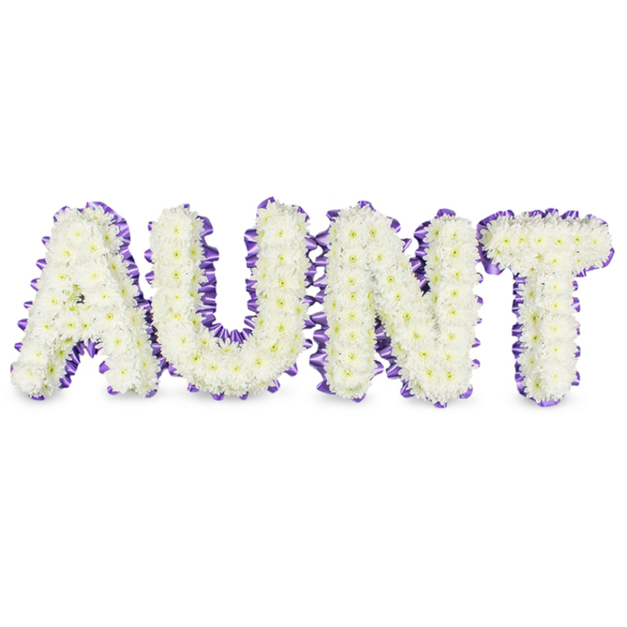 A carefully assembled tribute reads AUNT in large, uppercase letters, each character densely packed with petite white spray chrysanthemums that form a plush, ripple-free surface. The tiny petals create an impression of softness and continuity, while sporadic pale yellow centres add a whisper of warmth to the otherwise pristine white composition. Every letter is traced by a deep purple satin ribbon, the material ruffled and tacked to the frame so the edge forms a delicate, textured border that contrasts with the smooth mass of blooms. The arrangement sits against a spotless white background, and soft grey shadows underneath each letter reveal their dimensional depth and the solidity of the supports within. The overall mood is one of considered reverence: the white chrysanthemums speak to purity, remembrance, and comfort, while the purple ribbon introduces a thoughtful note of dignity. A subtle, green-tinged floral scent lifts gently from the chrysanthemums, reminiscent of early morning at a local park like Gerrards Cross Common. Intended for memorial use, the piece would read clearly at a funeral service or wake, offering a personalised, readable message of love. The craftsmanship - precise flower placement, careful ribbonwork, and balanced negative space - demonstrates the kind of bespoke funeral artistry the community expects from an experienced local florist.