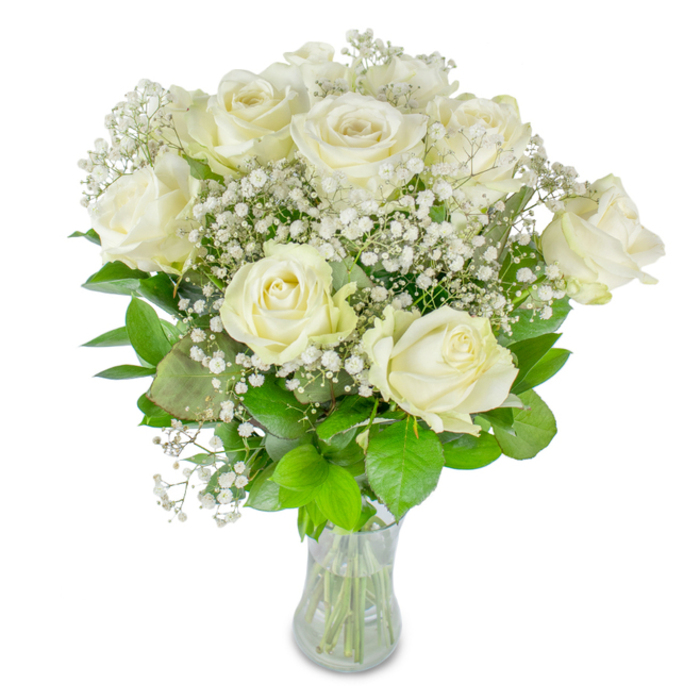 This harmonious assembly of lush white roses and airy baby's breath reads like a short, luminous story: roughly twelve pristine roses, their creamy petals unfolding with a soft, waxen perfection, are haloed by the fine, starry spray of Gypsophila. The baby's breath acts as a delicate lattice, its tiny blooms catching light and adding a feathery softness that contrasts with the roses' smooth, layered petals. Beneath and between these blooms lies a bed of verdant foliage - leaves varying from rich emerald to fresh lime, their satin surfaces and subtle veins offering a cool, grounding counterpoint to the pale blossoms. The bouquet is presented in a clear glass vase, deliberately simple, so the neatly trimmed green stems and the clear water level remain visible; this transparency reinforces a sense of honesty and freshness in the work. Set against a clean white background and lit by gentle, diffused light, the composition emphasises texture and form: the roses' curled edges, the baby's breath's airy clusters, and the leaves' quiet sheen. I imagine this arrangement finding a place at an intimate rehearsal dinner in a village hall near Gerrards Cross Common or as a quietly elegant centrepiece in a living room on Grange Road - occasions where subtlety matters more than spectacle. The scent is restrained, a tender breath rather than an embrace, which makes the bouquet suitable for weddings, milestone anniversaries, or moments of remembrance. From a florist's point of view, arranging such a bouquet is about balancing strength and delicacy to create a moment of stillness and radiance that lingers softly in the room.
