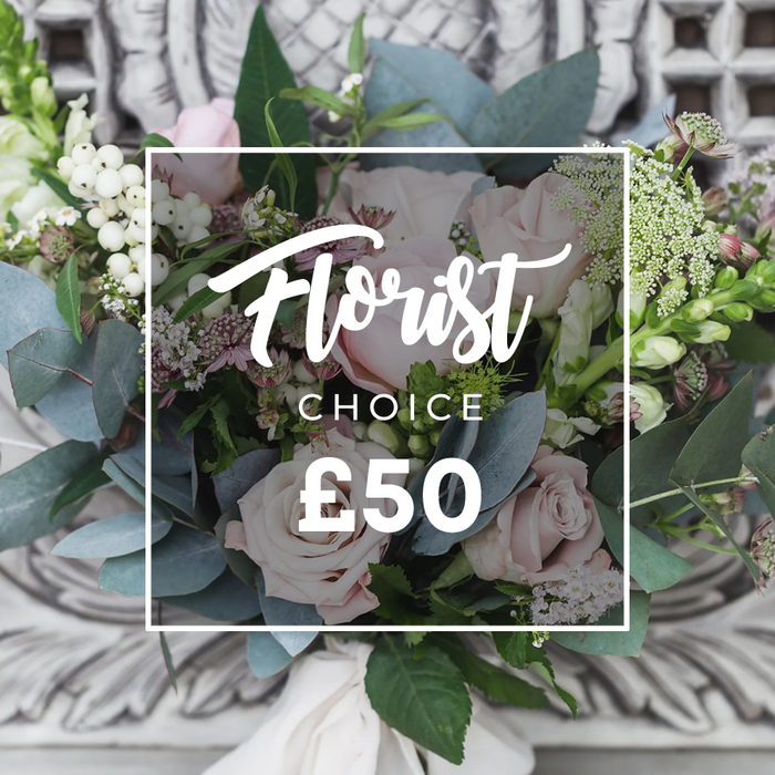 A lush, carefully arranged bouquet fills the frame here, set before an elegantly carved, pale stone or plaster background that suggests an upstairs parlour or the aged mantel of a Georgian home. Soft blush-pink roses dominate, their layered petals unfurling into romantic, sculptural blooms; around them clusters of bright white berries-likely snowberries-add crisp, luminous texture. Wisps of tiny white filler flowers, perhaps waxflower, drift through the arrangement like confetti, while abundant dusty blue-green eucalyptus leaves provide a cool foil to the warm rose tones with their rounded, silvery surfaces. Small, deeper pink and burgundy blossoms sit in the shadows to give depth, and taller green-and-white spikes peek from the sides, lending verticality and movement. The stems are bound with a cream-coloured fabric ribbon visible at the base, suggesting a hand-tied, bespoke finish. Over the bouquet a clean white rectangular frame contains elegant script reading Florist above uppercase CHOICE and clear pricing marked at £50, the on-image text indicating a curated Florist's Choice selection. This photograph carries a mood of refined, understated luxury-perfect for gifting on anniversaries, milestone birthdays, or as a thoughtfully chosen housewarming present for someone moving into a cottage near Gerrards Cross station or a family home by Denham. As a local florist I read it as an arrangement that balances softness and structure, scent and texture, ready for delivery across Gerrards Cross and neighbouring villages.