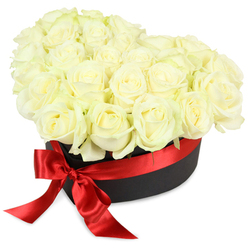 Effortlessly combining modern elegance with timeless romance, this heart-shaped bouquet is one of Gerrards Cross's signature floral experiences. Perfectly formed white roses-classic emblems of new beginnings and cherished memories-are arranged in sophisticated layers within a sturdy matte black box reminiscent of vintage hatboxes. Each bloom, from tightly closed bud to softly unfurling petal, displays a luminosity that recalls early morning light at Gerrards Cross Common, their creamy and ivory hues blending seamlessly with touches of subtle green. Gently nestled together, the blooms form a plush, domed texture that invites touch and promises a lingering, fresh floral scent. Wrapping the container is a scarlet red satin ribbon tied into a lush, glossy bow at the front-a bold streak of colour that signals heartfelt celebration. All composed against a crisp white background and bathed in soft, diffuse light, the arrangement gains a sense of clarity and balance. Created by local florists, this presentation is designed for moments that matter: romantic surprises along Fulmer Road, contemplative anniversaries, or thoughtful expressions of sympathy in the tranquil corners of Gerrards Cross. The details convey authenticity, care, and community knowledge, expressing both modern flair and enduring grace.