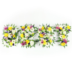 Hand-formed into the letters B, E, S, T and photographed head-on, this floral lettering is a study in contrast and tenderness against a pure white backdrop. Each letter is densely packed with fresh blooms: sunny yellow roses and gerbera daisies catch the eye with lively, warm tones; large, multi-petaled white chrysanthemums and cream gerberas create a soft, voluminous foundation; while delicate mauve and deep purple lisianthus or small chrysanthemums provide a muted, dignified counterpoint. Sprays of vivid pink spray roses or carnations peek through, adding moments of bright, affectionate colour. Dark green fern fronds rim each form, their airy fronds blending into the flowers to soften the silhouette; a discreet dark-green support frame is visible in places, most notably along the horizontal bar of the E and near the base of the T, hinting at the artisan structure beneath. The lighting is clean and even, bringing out the tactile qualities - the satiny sheen of rose petals, the layered softness of chrysanthemum petals, and the fine, almost fern-like texture of the greens. Presented as a sympathy or memorial display, this arrangement reads as both tribute and celebration, saying simply that the departed was 'the best' with warmth and restraint. As a local florist familiar with Gerrards Cross and nearby Burnham Beeches, I imagine this arriving for a service on Packhorse Road or being chosen by families from Chalfont St Peter seeking a sincere floral farewell.