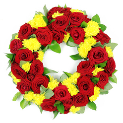 A full, circular funeral wreath packed with red roses and yellow chrysanthemums is displayed on a clean white background, the image focused so sharply that each petal and leaf appears freshly arranged for a service in Gerrards Cross. The wreath forms a solid ring of flowers with an open centre, symbolising a continuous bond and the unbroken nature of memory. Deep red roses are the principal flower, their velvety petals curled in elegant spirals that deepen from rich crimson to almost wine-red at the shadows, evoking both tenderness and solemn respect. Nestled between these roses are generous clusters of small, sunny yellow chrysanthemums, their fine, densely layered petals giving a soft, cushion-like feel that lightens the mood and adds warmth. Around and beneath the blooms, an abundant layer of greenery provides structure and depth: smooth, glossy green leaves, likely salal or laurel, interweave with slightly dusty, grey-green foliage reminiscent of eucalyptus, introducing subtle colour shifts and natural movement. Every stem is secured tightly, so the wreath looks sturdy and impeccably crafted, as though it has been prepared by a local Gerrards Cross florist who understands how important reliable, dignified tribute flowers are for families gathering near the parish church or the nearby crematorium. The white background and even lighting allow the colours to glow, making the contrast between the red and yellow particularly striking, while still maintaining a gentle, comforting tone. Overall, this wreath exudes a sense of heartfelt condolence and quiet honour, ideal for funerals, memorial ceremonies, or graveside remembrances where beauty and meaning need to stand side by side.