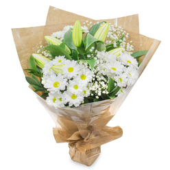 Against a bright, uncluttered white background, a serene bouquet of white and green flowers is captured in full detail, as if just arranged on a Gerrards Cross workbench before being sent out for delivery. The central focus is a mass of daisy-like white chrysanthemums, their petals layered and slightly curved, forming soft rounds around vivid yellow-green eyes that add a gentle touch of warmth. Threaded between them are several upright lily buds, still closed, their pale green sheaths flushed with hints of cream as they taper to delicate points. These buds introduce a graceful vertical line and a sense of anticipation, like the quiet pause before flowers open in a garden near West Common on a cool morning. Wisps of white baby's breath scatter through the bouquet, their miniature blooms clustered on fine stems that create a feathery, cloudlike veil over the other flowers. Beneath and around everything, lush green leaves provide structure and depth, their surfaces glossy and strong, framing the whites in rich, natural colour. The entire bunch is embraced by textured brown kraft paper, thoughtfully folded into a loose cone that suggests a walk back from a local market on Station Road, arms filled with fresh blooms. Over this sits a protective layer of clear cellophane, softly crinkled, catching glimmers of light and hinting at the stems inside. Securely tied at the base, the bouquet looks ready to be handed over with two hands and a quiet word of sympathy. The mood is one of peace, respect and gentle consolation, making this arrangement ideal for remembering a loved one with understated grace.