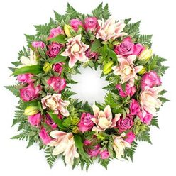 A meticulously crafted circular wreath is pictured head-on against a clean white backdrop, its ring of flowers so lush and continuous that it almost seems to float. The palette is centred on pinks and creams: clusters of roses in rich magenta, vivid fuchsia and soft pastel pink are threaded evenly throughout the design, their velvety petals tightly layered or gently unfolding in different stages of bloom. Between them, luxuriant double lilies open their broad, silky petals in tones of creamy ivory, blush and pale peach, some blooms turned slightly to the side so you catch a glimpse of their ruffled edges and softly speckled throats. Unopened lily buds, bright yellow-green and elegantly tapered, emerge from the foliage, hinting that the tribute will continue to evolve over the coming days. The flowers rest on a deep, verdant bed of greenery that follows the circle from edge to edge. Fine fern fronds fan out delicately, each leaflet adding a lace-like texture, while sturdy, glossy leaves in dark and mid greens provide structure and contrast. The white background and even lighting strip away distractions, making the colours appear saturated and serene, much like a wreath you might see resting near a graveside in St. Mary's churchyard or by a memorial bench on East Common in Gerrards Cross. Every detail of the arrangement feels intentional and composed, from the repetition of rose clusters to the careful spacing of lilies, creating a calm, graceful tribute suitable for funerals, celebrations of life, and quiet remembrance gatherings across the local community.