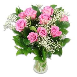 A fresh, romantic arrangement of pink roses and white baby's breath is captured against a spotless white backdrop, giving the bouquet a luminous, almost weightless presence. Ten to twelve roses in shades of clear, medium pink rise from the centre, each bloom at a slightly different stage of opening, from tight, hopeful buds to generous rosettes of layered petals that feel plush and velvety to the imagination. Interwoven among them are airy sprays of baby's breath, their tiny white blooms forming a mist-like veil that softens the stronger lines of the roses and reflects the gentle emotions of welcoming a new little one. Dark, glossy green foliage encircles the arrangement, the leaves crisp and well-defined, creating a lively contrast that makes the pink and white tones appear even more vivid. The bouquet is anchored in a simple clear glass vase partially filled with water, where the straight green stems are clearly visible, aligned with a florist's practiced hand. The overall shape is rounded and full, with no single flower overpowering another, suggesting both balance and care. The lighting is bright yet soft, casting no harsh shadows, as if the arrangement were sitting near a sunny window in a home off Orchehill Avenue or close to Gerrards Cross Common. The image evokes a sense of pure, joyful calm, making it easy to picture this bouquet delivered by a local florist as a baby girl gift, a nursery accent, or a thoughtful way to send love to new parents while keeping the focus firmly on the natural beauty of the flowers themselves.