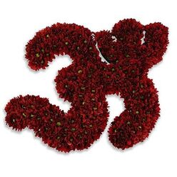A handcrafted floral emblem takes the shape of the sacred Om symbol, lovingly formed from deep red chrysanthemum blooms packed with quiet precision. Each curl and loop of the symbol is defined by hundreds of small, velvety petals - the chrysanthemums' layered structure creating a plush, almost sculpted surface that reads like garnet velvet. Tiny lime-green flower centers and whispered flecks of fresh foliage punctuate the crimson mass, offering delicate contrast and the sense of living texture. Against a stark white background the symbol's silhouette is striking; a soft, neutral shadow beneath it gives the impression that the offering is slightly raised, as if presented on a ceremonial altar. Up close you can almost sense the chrysanthemums' faint, comforting earthy scent-warm and steady rather than overtly floral-inviting contemplation and quiet solace. The overall effect is reverent and consoling: this is a floral prayer as much as a display, designed to hold space for mourning, healing, or a reflective ritual. As an experienced florist in Gerrards Cross I think of this arrangement brought to a small memorial at Stoke Poges or placed with care near a family home on a quiet lane off the High Street; it reads as a calm, carrying presence. The craftsmanship balances exacting structure with organic softness, making the Om both visually powerful and tenderly human - an offering that speaks of respect, continuity, and gentle consolation.
