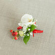 A meticulously crafted boutonniere rests on a softly textured, oat-coloured linen background, the kind of neutral fabric you might see on a rustic table in a Gerrards Cross country house. At the centre sits a pristine white Phalaenopsis orchid, its broad, velvety petals unfurled in a calm, open embrace. The orchid's throat glows with a gentle wash of creamy yellow and soft orange, drawing the eye inward and adding a quiet warmth to the otherwise cool white bloom. Nestled closely around it are fine clouds of baby's breath, each tiny white floret creating an airy halo that softens the composition and gives the buttonhole a romantic, almost mist-like texture. Deep, glossy green leaves in varied shapes fan out beneath and around the flowers, some tapering to a point, others more oval and smooth, grounding the design with natural structure. On one side, a vibrant cluster of round, red berries gleams like tiny ornaments, their polished skins catching the light and suggesting winter celebrations or a Christmas wedding along the leafy roads near Austenwood Common. A few paler green, berry-like buds peek through, hinting at freshness and new beginnings. The stems are neatly bound with a rich red satin ribbon, tightly wrapped and finished with a small knot, the short ribbon tails lying flat and orderly. The whole piece feels composed and ready to be pinned to a groom's lapel, a prom suit, or a formal jacket for a special gathering in or around Gerrards Cross, radiating quiet elegance, festive colour, and the thoughtful craftsmanship of an experienced local florist.