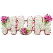 A quietly reverent standing tribute that spells out MUM in three large, connected block letters, photographed against a clean white backdrop so every detail reads clearly. Each letter is hand-built from densely packed, pristine white chrysanthemums whose small, feathery petals create a soft, cushiony surface and a uniform, luminous texture across the composition. The outer edges of every letter are finished with a ruffled ribbon in a tender, light pink that catches the eye and warms the arrangement without overpowering the purity of the white blooms. Nestled into the upper left of the first M, the base curve of the U, and the upper right of the final M are three coordinated clusters of deep fuchsia-pink roses, glossy fern-like foliage, and little coral-red hypericum berries; the rosebuds range from tight to just opening, adding movement and a velvety counterpoint to the crisp mums. A subtle dark-green supporting frame is visible between and behind the letters, hinting at the arrangement's standing structure and careful engineering. Soft, diffuse light lifts the pale whites and pinks, while the combined scent of clean chrysanthemums and the faintly sweet perfume of roses gives the piece a gentle, consoling presence.

Crafted with the sensitivity of a local florist, this MUM tribute reads as an expression of abiding love and remembrance suitable for a funeral, wake, or graveside service. The colour pairing - classic white for purity and the rosy accents for affection - creates a composed, dignified farewell. I imagine it set near a village church or quietly placed by the family at a service in Gerrards Cross, drawing comfort through its delicate textures and carefully balanced details.