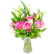 A luminous, hand-crafted bouquet rests in a simple clear glass vase against a crisp white backdrop, the composition radiating a quiet celebration of colour and scent. At the heart of the arrangement several large, fully opened deep pink roses unfurl like velvet cups, their petals graduating from soft blush at the edges to a richer fuchsia toward the centre. Interwoven among them are elegant white lily buds - some still tightly wrapped and sculptural, others just beginning to part and reveal their pristine, trumpet-shaped petals - promising a gentle, powdery perfume when they open. A generous sweep of mixed green foliage gives the bouquet a full, rounded silhouette: broad glossy leaves sit beside finer, lighter green sprigs that catch the light and create a soft, textural backdrop. Small, darker burgundy or reddish-brown accent buds are threaded through the greens, adding shadowed depth and a painterly contrast to the pinks and whites. The vase's tapered form and clear water make the neatly trimmed stems visible, reinforcing the freshness and craftsmanship of the arrangement. Soft studio light glances off satin petals and wetted leaves, suggesting a bright kitchen table or a polished mantelpiece on Gerrards Cross High Street, a gift that would uplift a living room near Burnham Beeches or bring gentle cheer to a Denham bedside. This bouquet feels like a thoughtful, joyful gesture - suitable for birthdays, anniversaries, or simply to say thank you - and conveys the tactile luxury of garden-fresh roses paired with poised white lilies.