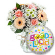 A bright, comforting 'Good Luck' gift pictured against a clean white backdrop: a generous bouquet sits slightly left in a clear glass vase, its neck finished with a rustic twine bow that softens the glass's cool shine. The arrangement mixes soft peach and light pink roses-petals folded like satin-alongside warm peachy-orange Gerbera daisies with their deep brown, textured centres. Sprays of fine white baby's breath (Gypsophila) spill through the composition like lace, while small clusters of crisp white and lime-green chrysanthemum florets add a lively, citrus-bright pop. Deep green foliage peeks through the blossoms, giving weight and contrast and a subtle green scent beneath the roses' gentle perfume. To the right and slightly overlapping the vase is a round metallic silver foil balloon, gleaming under soft studio light. Its surface is scattered with colorful hearts, stars and confetti-like shapes in blue, pink, yellow and orange; the central message reads Good Luck! in a playful, bubbly, multi-coloured font. Two of the letters are replaced by yellow smiley faces-one winking, the other sticking its tongue out-adding a mischievous, hopeful chuckle to the sentiment. A small KALEIDOSCOPE logo sits at the balloon's base. The overall effect is warm and encouraging-an arrangement that smells faintly floral, looks cheerfully optimistic and reads as a thoughtful wish for exams, interviews, farewells or fresh starts. As a florist I picture this being handed across Gerrards Cross High Street or tucked beside a station departure, a compact but heartfelt parcel of encouragement ready to brighten someone's new chapter.