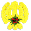 This image shows a lovingly crafted floral Khanda-a large, stylised Sikh emblem carefully formed from thousands of small, tightly packed bright yellow chrysanthemum blooms against a pure white backdrop. The arrangement reads as a single, warm plane of sunshine-coloured petals, each tiny blossom layered to create a plush, slightly three-dimensional surface that follows the circular chakkar, the central double-edged khanda, and the two crossed kirpans with precise, reverent lines. Nestled at the very centre is a concentrated cluster of five deep red roses, their velvety petals turned inward like a small, solemn heart; the roses sit upon and are framed by sprays of dark green fern fronds that add a cool, feathery contrast to the glowing yellow. Soft studio light picks out the petal textures and casts a gentle grey shadow beneath the tribute, giving the piece a grounded, tactile presence as though it might be carried into a gurdwara service or placed on a memorial table. There is a faint floral-sweet scent in the imagining-green, slightly sun-warmed chrysanthemum notes mingling with the classic, concentrated perfume of the roses-an aroma that quietly signals respect and remembrance. As a local florist in Gerrards Cross, I picture this design offered for ceremonial occasions across the village, from services near the station to quiet gatherings around Burnham Beeches and the Chiltern Hills, where families seek an emblematic, respectful tribute that honours Sikh faith and heritage with clarity, colour, and calm craftsmanship.