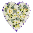 A generously proportioned, heart-shaped funeral tribute filled with white and cream flowers is photographed head-on against an uncluttered white background, giving the impression of a soft, glowing cushion of blooms. In the very centre of the heart, a single creamy white rose opens in perfect symmetry, acting as the emotional anchor for the entire design. Surrounding this central rose, layers of white carnations create a plush, comforting base, their ruffled petals overlapping closely so the arrangement appears rich and complete. Mixed within the carnations are white spider chrysanthemums whose slender, radiating petals and pale green centres break up the softness with a touch of airy texture. Between these feature flowers, smaller cream and ivory roses, along with delicate buds and filler blooms, are nestled carefully, ensuring that the heart shape remains beautifully defined from every angle. Silvery-green eucalyptus sprigs peek out between the flowers, bringing subtle movement and a cool blue-green hue that gently offsets the warm whites and creams, reminiscent of the calm greenery that borders the residential streets around Gerrards Cross station. The whole heart is outlined with a deep lavender to rich purple ribbon, pleated to create a scalloped, ruffled frame that adds structure and a sense of ceremony, often chosen by families seeking a dignified tribute. The craftsmanship suggests the practiced hands of a local florist, each bloom selected for freshness and placed with intention, suitable for delivery to a church, crematorium, or family home in Gerrards Cross. The tribute radiates a quiet, respectful beauty, expressing love, remembrance, and sympathy in a way that feels both traditional and deeply personal.