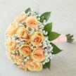 Resplendent in gentle peach and apricot tones, this expertly hand-tied bouquet embodies the romantic spirit of weddings and cherished celebrations across Gerrards Cross. Each rose opens in flawless formation, its petals blending seamlessly from soft pastel on the outer edges to a richer, more golden apricot at the core, creating a harmonious, sunlit gradient. Whisper-soft tufts of white baby's breath embrace and accent the roses, recalling the delicate lace of a bridal gown or the ethereal charm of Gerrards Cross in early summer. Surrounding the blooms, glossy emerald leaves lend structure and visual harmony, highlighting the lighter hues within. The stems are wrapped with care in a generous peach-hued satin ribbon, its plush texture adorned with a neat lattice of pearl-like beads that shimmer gracefully-an elegant finishing touch. Rested atop a finely woven, creamy-beige fabric backdrop, the bouquet's colours and artistry shine through, inviting feelings of hope, devotion, and timeless celebration. Its gentle fragrance-sweet and calming-offers a sensory prelude fit for treasured moments in Gerrards Cross.