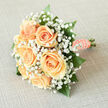 There is a quiet, almost tender magic to this bridal bouquet-a composition that feels as if a first perfect moment of spring in Gerrards Cross was gathered and tied by hand. Creamy peach roses sit tightly together at the heart of the design, their petals unfolding in delicate spirals and reflecting a gentle, creamy luminosity like sunlight filtered through the trees at Black Park. Surrounding them, a froth of white gypsophila drifts like mist, each tiny blossom softening the arrangement and lending an innocent, dreamlike quality. Sprays of glossy, emerald greenery thread through the blooms, anchoring the shape and making the peach tones appear even more luminous. The stems are lovingly swathed in peach satin ribbon, secured with a string of lustrous pearls that catch the light with every movement and add a timeless, tactile finish. You can almost feel the smooth ribbon beneath your fingers and imagine the light, floral scent rising up-fresh, cool, and infinitely gentle. Created with care by local hands and available through Flower Delivery Gerrards Cross for brides who favour subtle elegance, this bouquet works beautifully for a ceremony at the parish church, a garden reception near Chalfont St. Peter, or as an intimate keepsake. It reads as classic yet personal, an emblem of tenderness and optimistic beginnings crafted with an eye for balance, comfort, and quiet beauty.