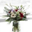 An artful floral arrangement, radiant with deep red roses and crisp white gerberas, stands proudly in a sparkling glass vase-its beauty amplified by the fresh, clear daylight so familiar to Gerrards Cross. Gentle accents of pale lavender lisianthus, some tightly budded, offer an airy contrast, while circular, silvery-green eucalyptus sprigs arc outward in a graceful, almost wild sweep reminiscent of the gentle nature that frames the area's parkland. Clusters of downy white filler blooms and lush structural greenery wrap the bouquet in a soft embrace, heightening its tactile appeal. The interplay of fragrant eucalyptus and mellow rose infuses the scene with a soothing, invigorating scent, evoking cherished moments-perhaps early-morning visits to local markets or the tranquility of St. James's Church gardens. The clear vase, revealing fresh stems immersed in sparkling water, completes the picture of enduring freshness. Whether given in gratitude, celebration, or remembrance, this bouquet, available for prompt delivery across Gerrards Cross, encapsulates a harmonious blend of artistic skill and heartfelt local connection.