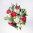 A hand-tied bouquet filled with crimson roses, pink-red carnations, snow-white daisies, and soft clouds of baby's breath rests against a neutral background, glowing as though it has just been set down on a sunny windowsill in Gerrards Cross. The roses are bold and velvety, their deep red petals spiralling tightly at the centre, while the carnations around them ruffle outward in feathery folds, adding movement and texture. Crisp white daisy-style chrysanthemums brighten the arrangement, their golden centres echoing early morning light over the Common. Threads of gypsophila weave delicately between the larger flowers, creating an airy, almost sparkling veil that softens every edge. Eucalyptus stems arc gracefully from the heart of the bouquet, their muted blue-green leaves and cool fragrance lending a modern, stylish contrast to the richer tones. Deeper green tropical foliage forms a lush collar, framing the blooms without overwhelming them, and giving the bouquet a confident, sculpted shape. The composition feels balanced and inviting, neither stiff nor untamed - you can almost imagine a local florist adjusting each stem on a workbench just off Packhorse Road. The overall mood is cheerful and optimistic, like opening the door to a loved one's surprise visit: perfect for birthdays, reunions after a long journey through Buckinghamshire, or simply brightening a favourite corner of a Gerrards Cross home. Light catches on the petals and glossy leaves, emphasising the freshness of the flowers and the gentle care with which they have been arranged, as though they have been gathered to hold a small but vivid celebration in your hands.