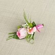 Beautifully styled to capture the essence of special days in Gerrards Cross, this delicate floral boutonniere rests softly on an off-white, textured linen-its simplicity letting the natural beauty shine. At its core sits a tightly wound rose, pastel pink petals forming a graceful spiral of romantic promise. It is flanked by a pale peach alstroemeria, each petal gently curving open to reveal subtle gold and dark markings that add depth and artistry. Interspersed among these main blooms, airy sprays of white baby's breath evoke a sense of classic elegance, while vibrant green button mums bring a cheerful freshness, their spherical forms contrasting with the more ruffled petals nearby. The arrangement is further enhanced by an array of lush green foliage: spiky grasses and feathery ferns reach outward, while broad, deep green leaves nestle below and support the blooms, some artfully folded for visual interest. The finishing touch is a rich, fuchsia satin ribbon securing the stems-a small and perfectly tied bow that symbolizes joyful occasions. Crafted for a wedding at the Memorial Centre or a memorable night at a Gerrards Cross prom, the piece exudes the hallmarks of expert local floristry: freshness, attention to detail, and a sense of subtle celebration. Presented in clear, even daylight, the boutonniere's gentle colors and delicate textures are ideal for those seeking a refined and romantic accessory for life's cherished moments in Gerrards Cross.