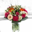 This bouquet is a vivid celebration-an explosion of colour and warmth reminiscent of the happiest moments spent in Gerrards Cross. Sun-bright orange gerberas reach out boldly, surrounding blushing pink roses and deep-magenta carnations whose velvety petals speak of luxurious comfort. Creamy ivory roses and subtle peach gerberas add elegance and underline the emotional softness, balancing the lively hues with quiet tenderness. The crisp, glossy greenery anchors the entire arrangement with a lush, abundant look, recalling the leafy avenues and open gardens characteristic of Gerrards Cross's residential charm. Illuminated by radiant daylight, each petal reveals intricate veining and delicate texture; the bouquet almost seems alive, breathing energy into any space it enters. Perfect as a gesture for a milestone birthday, anniversary, or simply to let someone know they are cherished, this local florist-crafted bouquet radiates happiness, harmony, and an unmistakable sense of place-bringing a little bit of Gerrards Cross's sunshine and community spirit into the recipient's home.