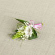 A petite, thoughtfully assembled boutonniere lies on a pale, woven linen background, the soft oatmeal tones allowing the flowers to stand out with quiet clarity. At its heart is an open white alstroemeria-like flower, the petals smooth and slightly curved, delicately brushed with fine reddish-brown stripes that create a sense of depth when you imagine tracing them with your fingertips. Clustered close by are smaller white buds and partially opened blossoms, reminiscent of lily-of-the-valley or campanula, their rounded shapes suggesting purity and new beginnings. Airy sprays of white baby's breath weave between them, forming a gentle, mist-like frame that softens the entire composition. On the left side, a vivid green, cone-shaped spray of tightly packed buds, similar to Ornithogalum, provides an eye-catching vertical accent and a fresh, garden-inspired texture, like something gathered from a morning walk near East Common in Gerrards Cross. Broad, glossy dark green leaves and slender arcs of bear grass cradle the blooms, curving outward in an easy, natural rhythm. At the base, a glossy pink satin ribbon wraps the stems and is finished in a neat, elegant bow, the colour adding a hint of playful romance suited to weddings, proms, or milestone celebrations. The lighting is gentle rather than harsh, bringing out the subtle sheen of the ribbon, the velvety petals, and the woven weave beneath. This floral accent feels handcrafted with care, the kind of corsage a local florist might prepare for a ceremony at a nearby church or a quiet family gathering at home in Gerrards Cross.