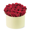 A luxurious and vibrant floral arrangement of deep red roses sits in a round pale cream-colored box, photographed from a slightly elevated three-quarter angle against a clean white background. In Gerrards Cross, this is the kind of bouquet that feels both timeless and contemporary, a statement piece for a thoughtful gift. The bouquet contains two dozen or more velvety crimson roses, each bloom tightly furled and just opening to reveal its richest, ruby centre. They are arranged to completely fill the cylindrical box, creating a dense dome of colour that rises slightly above the rim, a sign of generous sourcing and careful hand-craft. Hints of green foliage peek between the dark red petals, adding a touch of natural contrast and freshness that keeps the arrangement feeling alive rather than perfectly tamed.

The circular box itself has a smooth matte finish, giving it a sophisticated, premium feel that evokes a classic hat box design often chosen for luxury flower delivery in our area. The entire display is captured from a slightly elevated, three-quarter angle, prominently centered against a plain white background to ensure the focus remains on the elegant flowers and their chic packaging. This image embodies the essence of a thoughtful gift, symbolising love, passion, and romance, making it an ideal visual for articles about anniversary gifts, Valentine's Day flowers, luxury flower delivery services, or special occasion bouquets in Gerrards Cross and surrounding Bucks villages. Delivery is available across Gerrards Cross, Beaconsfield, and Jordans, ensuring this luxurious bouquet can arrive promptly for anniversaries, Valentine's, or spontaneous acts of love.