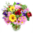 A vibrant mixed bouquet rises from a clear glass vase, carefully arranged and photographed against a pristine white backdrop so every flower stands out. At the heart, deep red roses with plush, velvety petals create a rich, romantic centre, their colour bringing to mind the warm glow of a sunset over Gerrards Cross Common. Alongside them, two bold yellow gerbera daisies with dark brown-orange centres shine brightly, radiating cheerful, sunlit energy. Around these focal blooms, abundant clusters of soft pink daisies or chrysanthemums add a generous layer of texture, their fine petals and tiny yellow eyes forming a cloud of gentle pastel colour that softens the composition. Threading through the bouquet are graceful purple and lavender lisianthus, their bell-like, slightly ruffled blooms adding a cool, elegant note and a sense of depth, as if the flowers are quietly unfolding in slow motion. Bright red Hypericum berries are dotted through the design like little round ornaments, introducing playful contrast and an extra tactile element. The entire arrangement is cradled by mixed greenery: broad, dark leaves give it structure and weight, while narrower, light-green sprigs bring movement and freshness, echoing the look of foliage you might see on a walk down Bulstrode Way. The transparent vase reveals the clean, trimmed stems and clear water, underscoring the care taken in preparation and the bouquet's fresh, just-arrived feel. Crafted with a balance of colour, shape, and texture, this arrangement feels joyous yet composed, ideal for celebrating a birthday, sending congratulations, or simply brightening someone's day in Gerrards Cross with a burst of natural beauty.