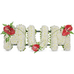A dignified, three-dimensional floral tribute spells the word 'MOM' in bold capital letters, set against a clean white backdrop. Each letter is constructed from hundreds of small, pristine white spray chrysanthemums packed closely to form a soft, cloud-like surface that reads as pure and peaceful from a distance and finely textured close up. The dense white heads create a gently undulating plane, their petals whispering a faint green perfume of freshly cut blooms beneath soft daylight. Interspersed to arrest the eye are three glossy red anthuriums, their heart-shaped spathes and pale yellow-white spadices providing a warm, vivid punctuation against the white field. One anthurium crowns the upper left of the first 'M', another nestles at the base of the central 'O', and a final bloom balances the upper right of the second 'M', creating a visual triangle of affection. Around each red focal point, clusters of dark green foliage - slender arching blades, feathery fern fronds and broader leaves - add depth and a shadowed contrast that reveals the subtle dark frame supporting the letters. Thin, graceful grass stems arc between the red blooms like a quiet connecting thread, guiding the eye across the tribute and unifying the composition. The overall effect is one of tender respect and calm reflection, suitable for a funeral service, wake or graveside, where the balance of white purity and red warmth reads as love remembered. As a local Gerrards Cross florist would tell you, this arrangement carries the hush of a chapel and the intimacy of a family goodbye, lending comfort through careful craftsmanship and thoughtful placement.