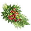 Displayed against a plain white background, this long, tapering funeral spray feels both stately and tender, echoing the kind of thoughtful floral tribute that might accompany a final farewell in Gerrards Cross. The arrangement is shaped like a gentle teardrop, wider at the centre and gradually narrowing at each end, giving a sense of movement and flow. At its heart lie deep red blooms: classic roses with velvety petals, some just beginning to open, intermingle with striking red gerbera daisies whose darker centres add depth, and clusters of softly ruffled red carnations. These rich scarlet and crimson tones suggest love, honour, and the gravity of the occasion. Nestled among the reds are clusters of lime green chrysanthemum pompons, their small, round heads almost glowing against the darker flowers, offering a modern, fresh twist that keeps the composition from feeling too sombre. Tiny white filler flowers, like little stars of light, are threaded delicately throughout, lending softness and airiness. Surrounding this central mass of blooms is a generous frame of greenery: broad, glossy dark green leaves, feathery fern fronds, and varied foliage that create a lush backdrop. At the lower right, long, slender leaves are artfully splayed in a fan, reinforcing the elongated silhouette, while at the upper left a vertical bundle of green stems or leaves rises upward, bound together and accented with a single broad leaf wrapped around them for a contemporary, structured feel. This refined spray would be fitting as a casket adornment or a prominent standing tribute for a memorial or funeral service in and around Gerrards Cross, expressing sympathy and remembrance with quiet grace.