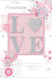 This anniversary card is a tender tribute to lasting romance, its design echoing the refined yet cosy charm found across Gerrards Cross and its tree-lined streets. At the centre of the front cover, the word LOVE appears in soft, raised glitter, giving each letter a tactile, velvety sparkle. The letter O is transformed into a shimmering silver heart, gently textured so it appears almost jewellery-like against the pastel backdrop. The background itself blends muted blush pinks with cool silvery greys, creating a serene palette reminiscent of soft evening light over Gerrards Cross Common. Around the central word, delicate illustrated flowers unfurl in blush and mauve tones, their petals rendered with a watercolour softness that seems to fade tenderly at the edges. Fine lines form flowing stems and graceful swirls, while tiny butterflies and swirling flourishes add a sense of lightness, like petals caught in a gentle breeze. The arrangement of the motifs feels carefully composed, much like an anniversary bouquet arranged by a skilled local florist, with blooms clustered thoughtfully around the heart and letters. Elegant script on the card reads On Our Anniversary and I love you today and always, the lettering slender and refined, mirroring the slender stems of the drawn flowers. Subtle hints of silver highlight key details, catching the light as though brushed with moonlight, and adding just enough shimmer to make the design feel special without overwhelming its softness. This card carries the quiet intimacy of a private celebration, perfect for honouring a shared journey and years of love lived together in Gerrards Cross.